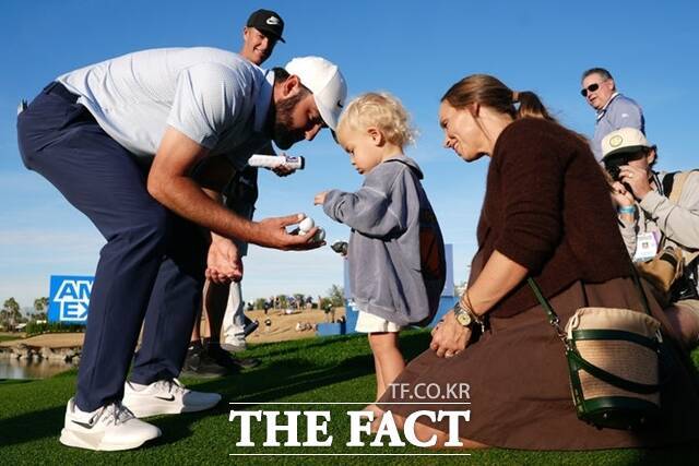 셰플러(왼쪽)가 우승을 확정지은 직후 그린 주변에서 아들에게 공을 건네고 있다./AP.뉴시스