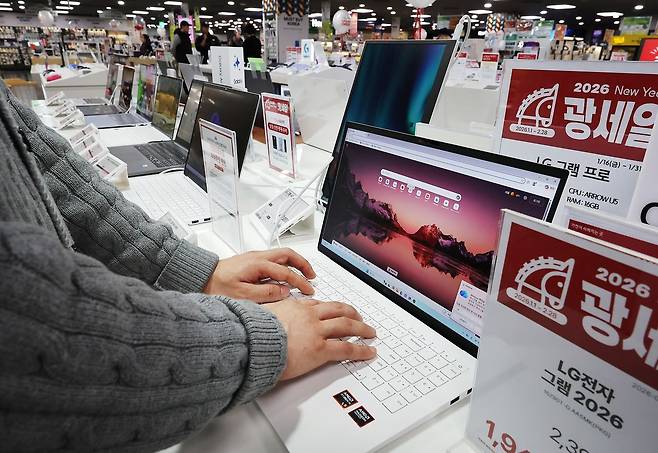 전세계적인 인공지능(AI) 열풍으로 메모리 반도체 수요가 급증하면서 스마트폰과 PC 등 주요 IT 기기 가격이 줄줄이 오를 것이라는 전망이 나온다. 지난 25일 서울의 한 마트에서 고객이 노트북을 살펴보고 있다.   연합뉴스