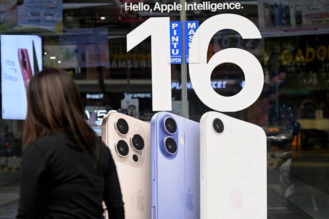 2025년 4월 12일 인도네시아 발리 섬 덴파사르의 한 매장에서 한 여성이 애플 아이폰 16 포스터 옆을 지나가고 있다. (사진=AFP)