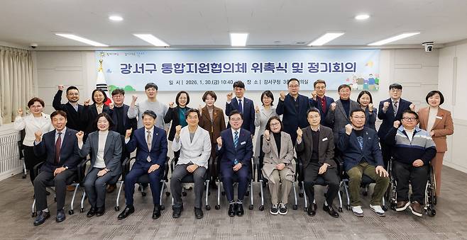 강서구 통합지원협의체 위촉식 및 정기회의에 참석한 사람들이 주먹을 쥐고 환호하는 모습이 담긴 단체 사진이다. 사진 상단에는 ‘강서구 통합지원협의체 위촉식 및 정기회의’라는 텍스트가 적혀 있다.