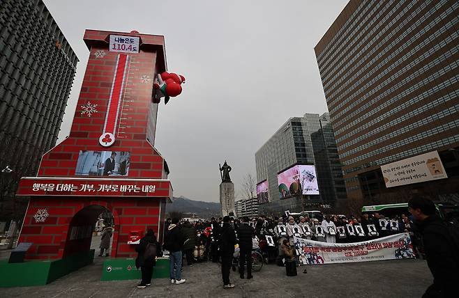‘동자동 쪽방 공공주택 촉구 결의대회’가 서울 종로구 광화문광장에서 열리고 있다. 왼쪽으로 목표를 넘은 ‘희망 2026 나눔캠페인\'의 사랑의 온도탑이 보인다.