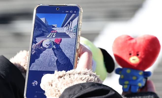 지난달 22일 서울 종로구 세종문화회관 계단에서 일본인 관광객이 오는 3월  복귀 공연을 하는 방탄소년단(BTS)의 홍보물을 배경으로 기념사진을 찍고 있다. 연합뉴스