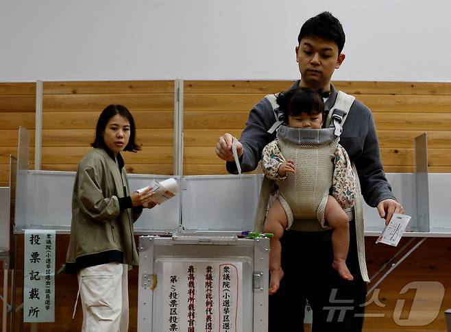 일본 도쿄의 한 투표소에서 한 남성이 아기띠를 메고 제50회 중의원 선거 투표에 참여하고 있다. 2024.10.27/ ⓒ 로이터=뉴스1 ⓒ News1 권진영 기자