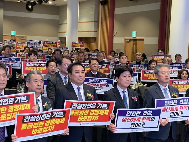 대한전문건설협회 인천시회 제41회 정기총회 및 건설산업 불공정 생산구조 정상화 결의대회에 참석한 조흥수 인천시회장(앞줄 오른쪽 두 번째)와 윤학수 중앙회장(〃 세 번째) 등이 불공정한 건설업 경쟁체제의 개선을 요구하는 손팻말을 들고 있다. /대한전문건설협회 인천시회 제공.