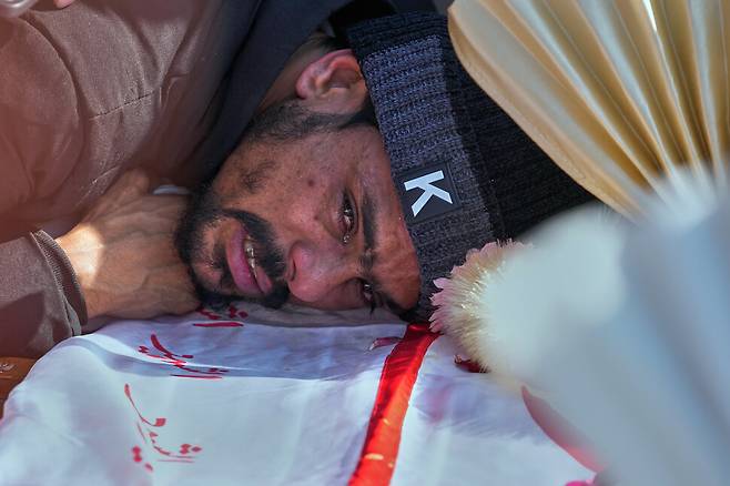 7일(현지시각) 파키스탄의 수도 이슬라마바드에서 한 남성이 전날 자살 폭탄 테러로 숨진 친족의 관 위에 엎드려 슬퍼하고 있다. AP 연합뉴스