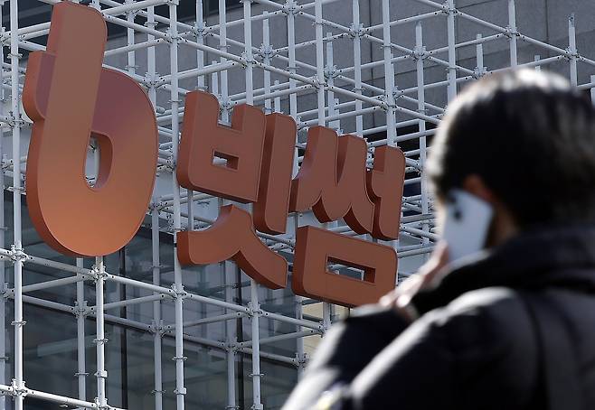 The Bithumb company logo is seen as a pedestrian walks by the Bithumb Lounge in Gangnam District, southern Seoul, on Feb. 9. [NEWS1]