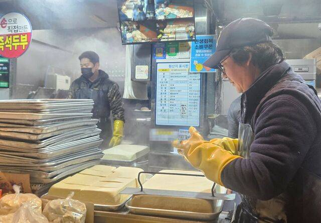 서울 마포구 망원시장의 두부 가게 직원 최창훈(44·오른쪽)씨가 지난 7일 두부를 자르기 위해 고무장갑을 끼고 있다.