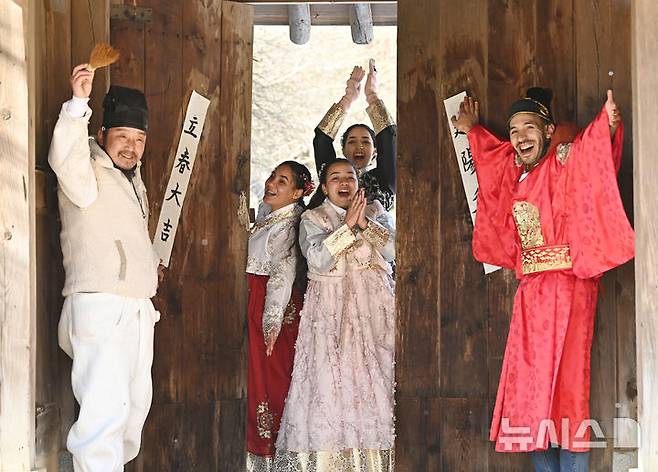 [용인=뉴시스] 김종택 기자 = 절기상 입춘을 이틀 앞둔 2일 경기 용인시 한국민속촌에서 외국인 관광객들이 입춘첩을 대문에 붙이고 있다. '입춘대길 건양다경(立春大吉 建陽多慶)'은 '봄이 시작되니 크게 길하고 경사스러운 일이 많이 생기길 기원한다'는 의미를 갖고 있다. 2026.02.02. jtk@newsis.com