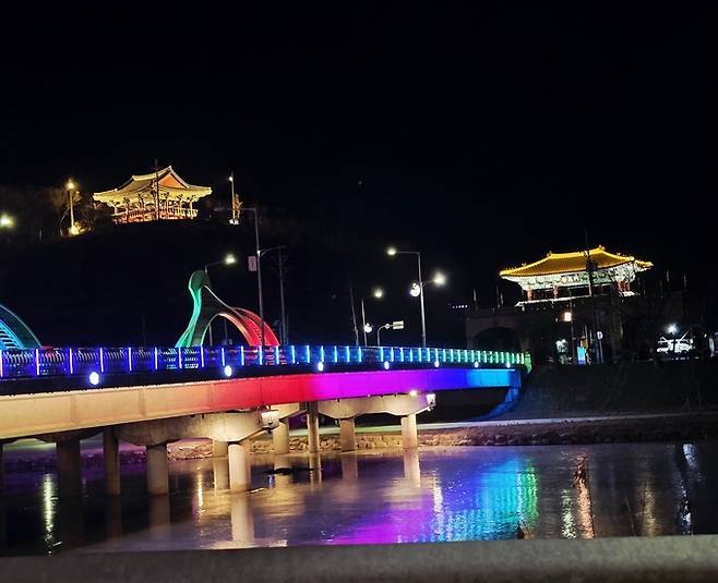 ▲ 경북 의성군 의성읍 남대천 일대에서 LED 조명이 설치된 교량과 하천 수면에 비친 야경, 인근 누각 조명이 어우러지며 야간 산책형 수변 경관을 형성하고 있다. 김동현 기자 jhass80@kyongbuk.com