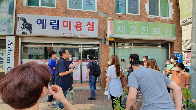 (주)퍼즐랩 권오상 대표가 ‘마을 도슨트 도보 투어’ 신청자들에게 제민천 인근의 오래된 상가들을 설명하고 있다. 이 투어에서는 충남 공주 원도심에 남아있는 옛 유적지와 건축물은 물론 마을에 새롭게 정착한 청년들의 창업공간을 둘러보는 일정으로 진행된다. 퍼즐랩 제공