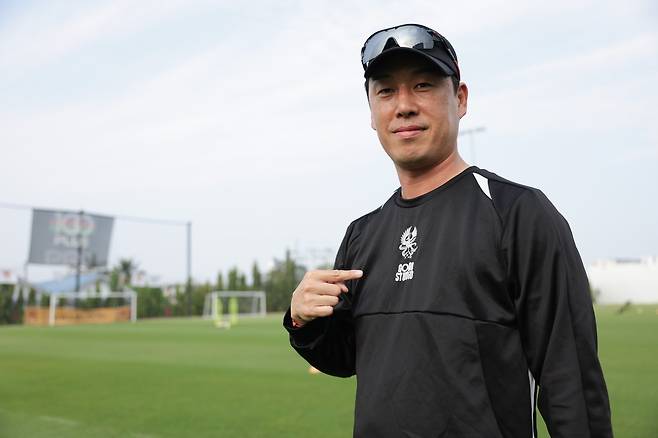 지난달 태국 후아힌에서 열린 1차 동계전지훈련서 상의 엠블럼을 가리키며 각오를 다지는 이정규 광주 감독. 사진제공|한국프로축구연맹