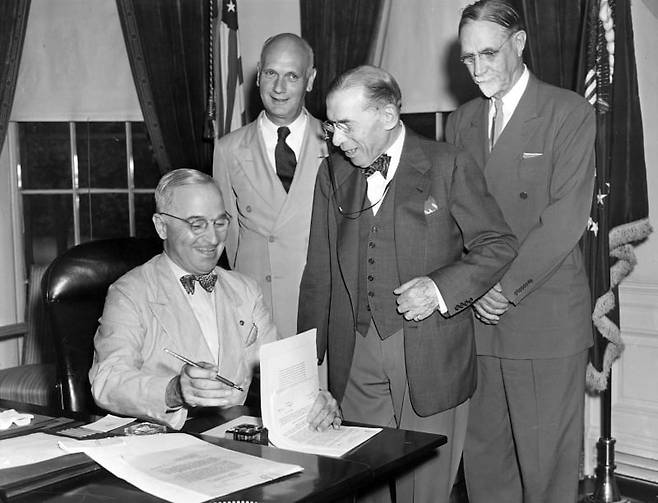 1947년 7월 해리 트루먼(맨 왼쪽) 미국 대통령이 집무실에서 ‘국제난민기구(International Refugee Organization)에 대한 미국의 가입과 참여를 규정하는’ 상원 공동결의안 77호에 서명하고 있다. 맨 뒷줄에 선 사람이 존 힐더링 미국 국무성 점령 지역 담당 차관보. /미국 해리 S. 트루먼 박물관