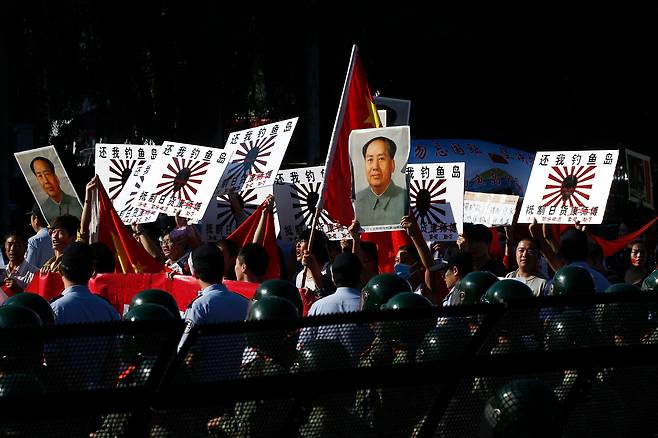 지난 2012년 9월  베이징 일본 대사관 밖 거리에서 행진하는 반일 시위대가 고(故) 공산당 지도자 마오쩌둥의 초상화와 중국 국기, 그리고 “댜오위다오(釣魚島)를 돌려달라, 일본 제품 불매운동”이라고 적힌 포스터를 들고 있다./ AP 연합뉴스