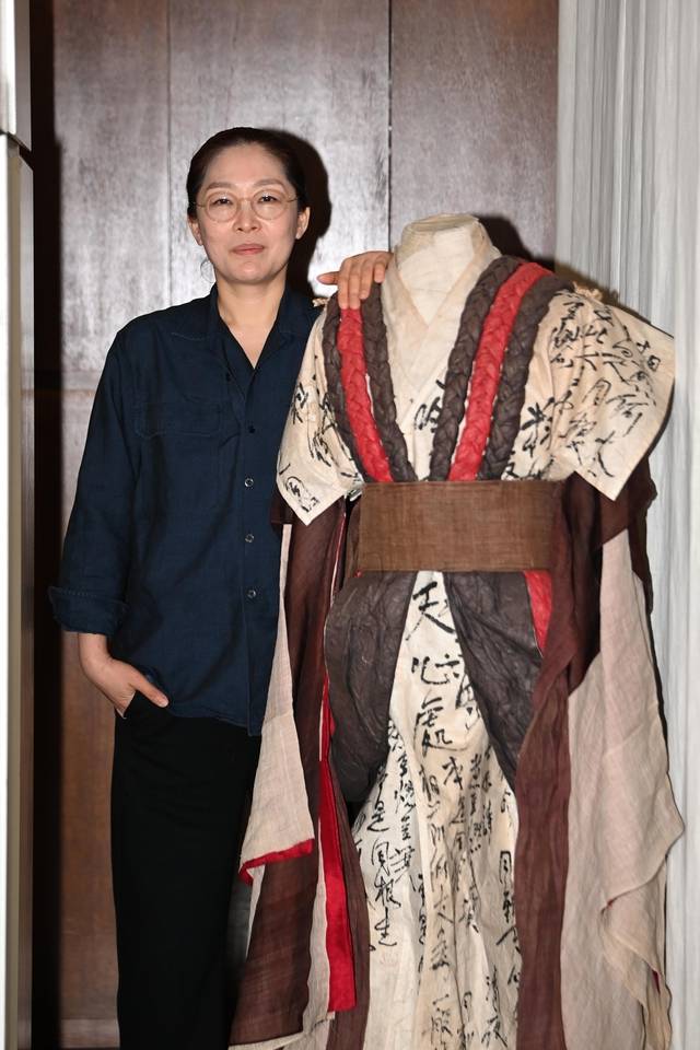 뮤지컬 ‘몽유도원’에 참여한 이진희 디자이너가 자신이 제작한 의상 옆에서 포즈를 취하고 있다.  문호남 기자