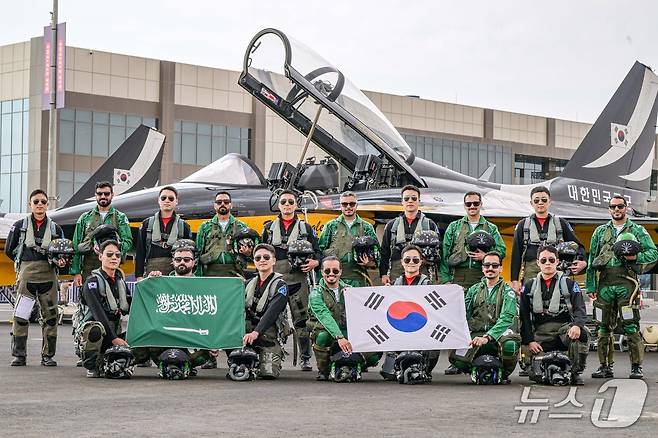 대한민국 공군 특수비행팀 블랙이글스가 지난 8일부터 12일(현지시간)까지 사우디아라비아에서 열리는 ‘세계방위산업전시회'(WDS 2026)에 참가해 에어쇼를 선보였다. 사진은 지난 2월 7일(토) 진행된 '블랙이글스-사우디 호크스(Saudi Hawks) 지상교류 행사'에서 블랙이글스 조종사들과 사우디 호크스 조종사들이 T-50B 항공기 앞에서 양국 국기를 들고 함께 기념촬영을 하고 있는 모습. 2026.2.13./ⓒ 뉴스1(공군 제공)
