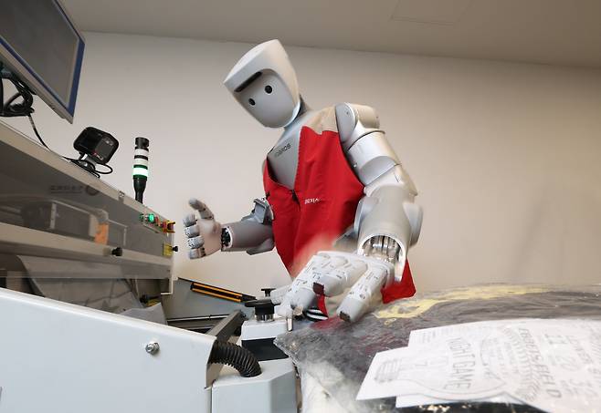 지난달 29일 서울 광운대 누리관 로봇제어실험실에서 인간형 로봇 '이그리드-C'가 자동 택배 포장 기계인 '오토 배거'를 버튼으로 조작하면서, 폴리백(작은 물건용 비닐 포장재) 포장법을 학습하고 있다. 하루 20~30번씩 원격 조종을 통해 다양한 색상·형태의 물건을 포장하며 '연습' 중이다. /장경식 기자