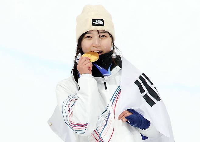 Choi Ga-on of Korea bites down on the gold medal in the women’s snowboard halfpipe final at the 2026 Milan-Cortina Winter Olympics on Feb. 12. [NEWS1]