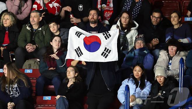 6일(현지시간) 이탈리아 밀라노 아이스 스케이팅 아레나에서 열린 2026 밀라노·코르티나담페초 동계올림픽 피겨 스케이팅 팀 이벤트(단체전) 여자 싱글 쇼트프로그램 신지아의 연기를 앞두고 관중석의 한 관람객이 태극기를 흔들며 응원하고 있다. 2026.2.6 ⓒ 뉴스1 김진환 기자