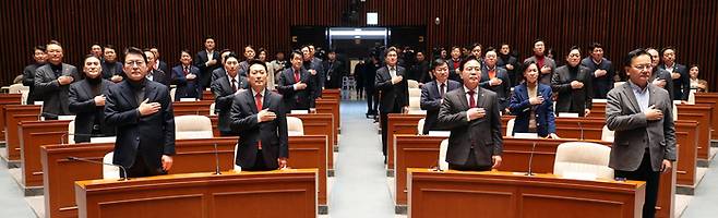 장동혁 대표와 송언석 원내대표를 비롯한 국민의힘 의원들이 지난 12일 국회에서 열린 의원총회에서 국기에 경례하고 있다. [연합뉴스]