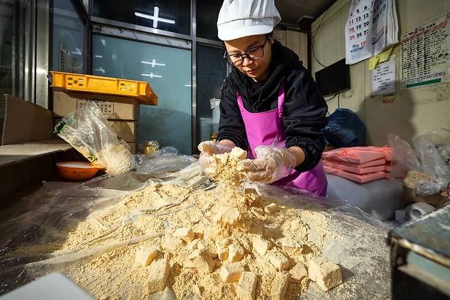 조 기자가 인절미에 콩가루를 묻히고 있다. 떡 모양이 망가질까 봐 살살 묻히니 한 직원이 "팍팍! 팍팍 버무려야 골고루 가루가 묻지"라고 했다. /이건송 영상미디어 기자