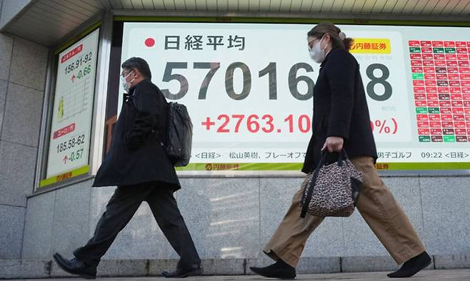 시민들이 지난 9일 일본 도쿄의 한 증권사의 닛케이225지수를 표시한 전광판 앞을 지나가고 있다. AP연합뉴스
