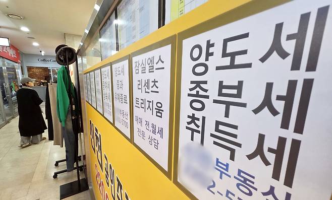 서울 시내 한 공인중개사 사무실 외벽에 부동산 관련 세금과 아파트 매매 물건 등의 안내문이 게시되어 있다. [연합]