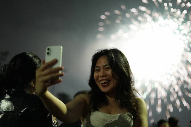 17일(현지시간) 베트남 하노이에서 한 여성이 병오년(丙午年) ‘말띠 해’를 반기는 화려한 불꽃놀이를 배경으로 셀카를 찍고 있다. AP연합