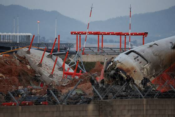 The wreckage of the Jeju Air aircraft that slid off the runway and crashed at Muan International Airport lies near a concrete structure it crashed into, in Muan, South Jeolla, on Dec. 30, 2024. [REUTERS/YONHAP]