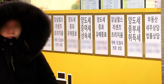 서울 잠실에 위치한 공인중개사 사무실 유리 벽에 부동산 관련 세금과 아파트 매매 물건 등의 안내문이 게시되어 있다.[연합]