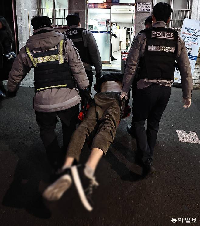 14일 새벽 서울 용산구 이태원파출소로 한 취객이 들것에 실려 들어오고 있다. 인사불성이 돼 몸을 가누지 못하는 이 취객을 파출소로 옮기기 위해 경찰관 4명이 투입됐다. 양회성 기자 yohan@donga.com