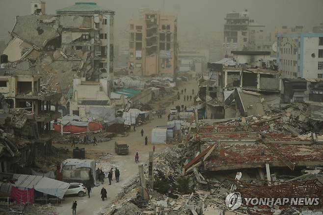가자시티에서 이스라엘군 공습으로 파괴된 거리를 걷는 팔레스타인 주민들 [AP=연합뉴스. 재판매 및 DB 금지]