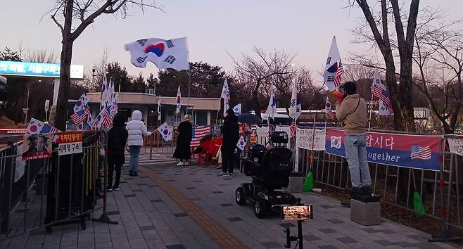 유튜버와 시민들이 19일 저녁 6시께 서울구치소 앞에서 태극기와 성조기를 흔들며 “대통령을 석방하라”고 외치고 있다. 이준희 기자