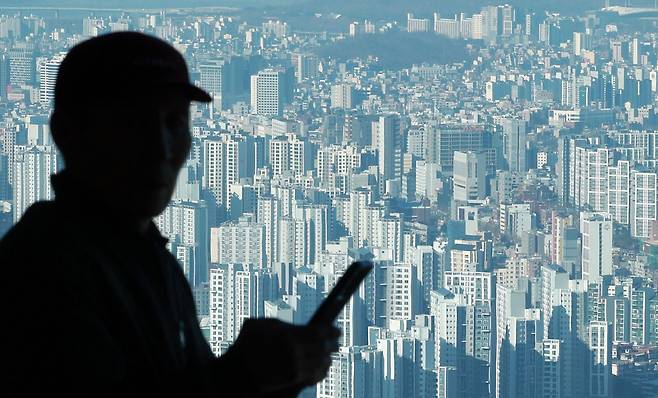 지난 19일 서울 남산 N서울타워에서 시민이 아파트단지를 바라보고 있다. [연합]
