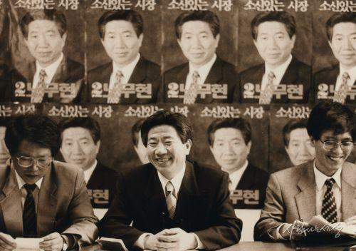 노무현 민주당 부산시장 후보가 1995년 6월 ‘소신있는 시장’이라는 선거 포스터가 붙은 사무실에서 활짝 웃고 있다<노무현재단>