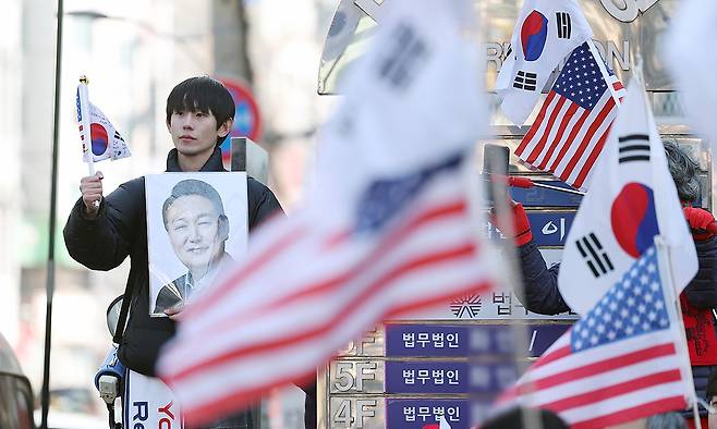 내란 우두머리 혐의로 기소된 윤석열 전 대통령의 1심 선고가 열리는 지난 19일 서울 서초구 서울중앙지방법원 인근에서 지지자들이 태극기와 성조기를 들고 있다. 연합뉴스