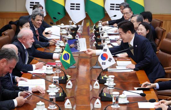 이재명 대통령이 23일 청와대에서 열린 한-브라질 확대정상회담에서 룰라 브라질 대통령 요청으로 책에 사인한 뒤 전달하고 있다. 2026.2.23 연합뉴스