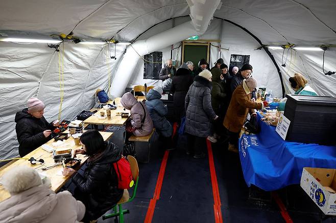 지난달 30일(현지시간) 우크라이나 키이우에서 최근 러시아의 미사일·드론 공격으로 주요 민간 기반시설이 타격을 입어 정전이 발생한 가운데, 주민들이 정부가 운영하는 인도적 지원 거점의 텐트 안에서 따뜻한 식사를 받고 있다. 로이터=연합뉴스