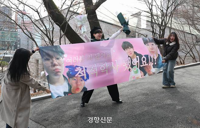 이화여자대학교에서 2025학년도 전기 학위수여식이 열린 23일 이화여대 교정에서 한 졸업생이 학우들이 만들어준 현수막과 함께 기념사진을 찍고 있다.