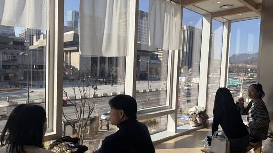 People enjoy the view of Gwanghwamun Square while having coffee at the Oats Coffee cafe located on the second floor of the KT Gwanghwamun Building. [WOO JI-WON]