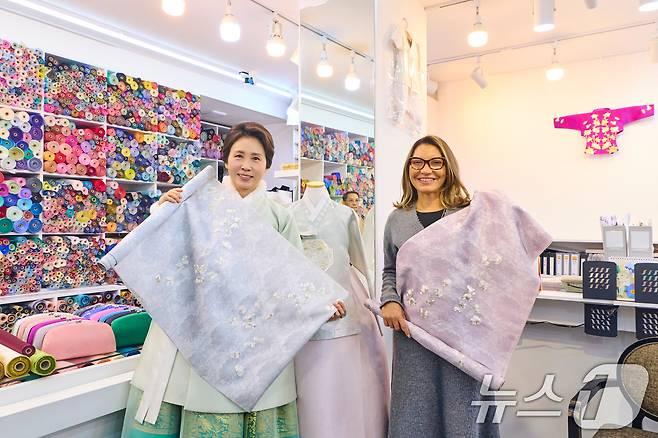 김혜경 여사와 루이스 이나시우 룰라 다시우바 브라질 대통령 부인 호잔젤라 다시우바 여사가 21일 서울 종로구 광장시장 내 한복가게를 찾아 원단을 들고 기념촬영을 하고 있다. (청와대 제공. 재판매 및 DB 금지) 2026.2.21 ⓒ 뉴스1 이재명 기자