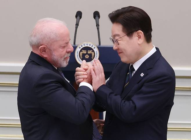 이재명 대통령이 23일 청와대에서 열린 루이스 이나시우 룰라 다시우바 브라질 대통령 국빈 방한 환영 만찬에서 답사를 위해 이동하는 룰라 대통령과 손을 맞잡고 있다. 연합뉴스