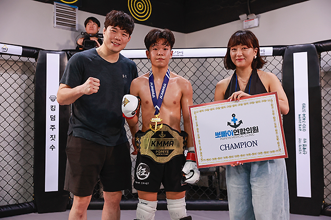 이영웅이 2024년 7월 초대 KMMA 플라이급 챔피언으로서 타이틀 1차 방어 성공 후 김대환 UFC 해설위원, 후원사 FBS’M 빅토리아 윤 디렉터와 기념 촬영을 하고 있다. 사진=스탠다드앤드프로그레스 스포츠에이전시 제공