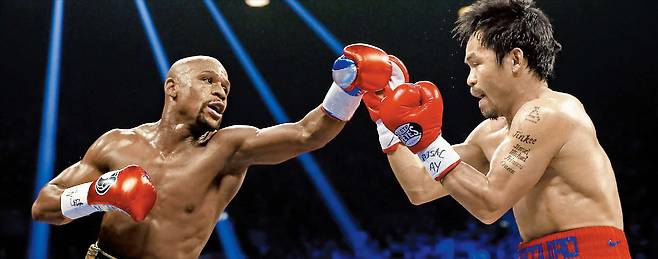 2015년 미국 라스베이거스에서 열린 웰터급 통합 타이틀전에서 플로이드 메이웨더(왼쪽)가 매니 파키아오에게 주먹을 뻗은 모습. 두 복싱 전설은 오는 9월, 11년 만에 재대결을 펼친다./게티이미지코리아