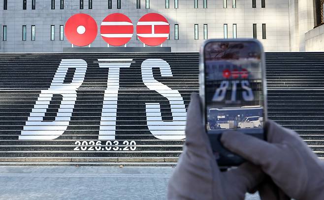 서울 종로구 세종문화회관 계단에 설치된 방탄소년단(BTS)의 정규 5집 컴백을 알리는 홍보물을 배경으로 관광객들이 기념 촬영하고 있다. /뉴스1