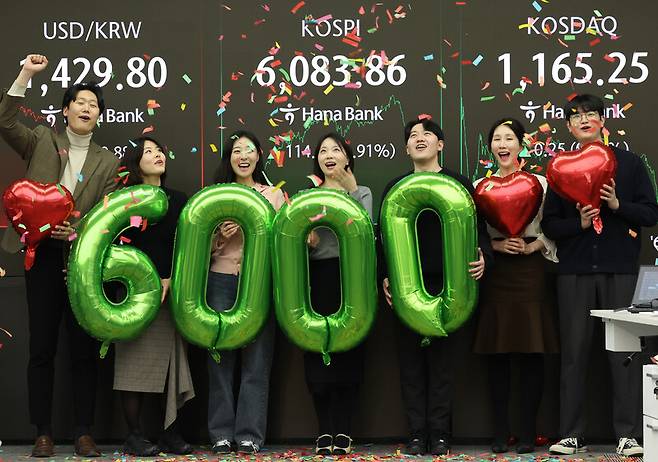 코스피가 사상 처음으로 6000을 돌파한 25일 서울 중구 하나은행 딜링룸에서 딜러들이 기념 세리머니를 하고 있다. 연합뉴스