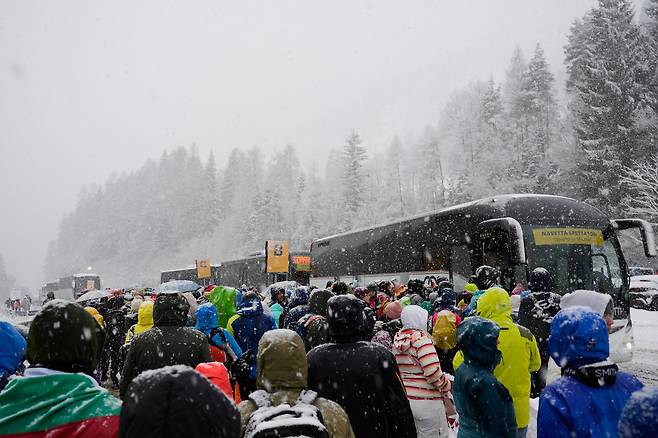 19일(현지시간) 이탈리아 프레다초에서 열린 2026 동계올림픽 노르딕복합 팀 스프린트 스키점프 경기를 관람한 뒤 관중이 눈이 내리는 가운데 셔틀버스를 타기 위해 줄지어 서 있다. AP