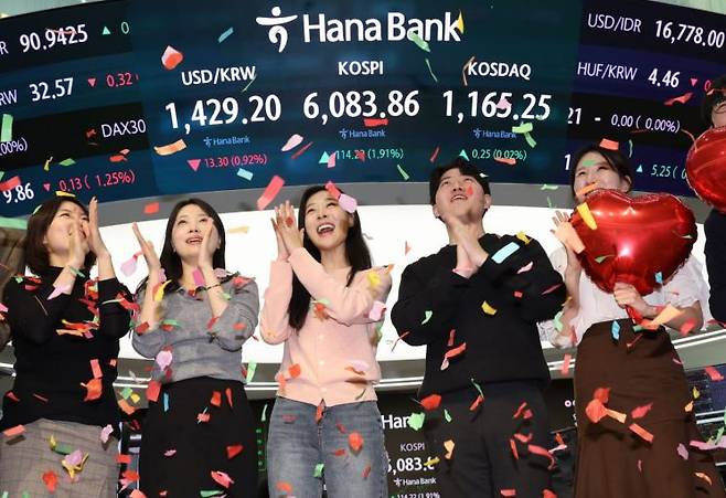 코스피가 사상 처음으로 6,000을 돌파해 거래를 마친 25일 서울 중구 하나은행 딜링룸에서 딜러들이 기념 세리머니를 하고 있다. 연합뉴스