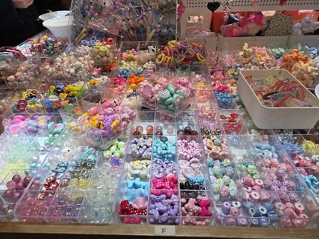 투명한 아크릴 칸막이 상자 안에 형형색색의 비즈와 참 장식들이 빼곡히 담겨 있는 모습. ⓒ데일리안 남가희 기자