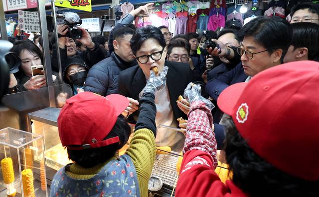 한동훈 전 국민의힘 당대표가 27일 오후 대구 중구 서문시장에 도착해 순회하는 와중 상인들이 건네는 음식을 먹고 있다.[연합뉴스 사진]
