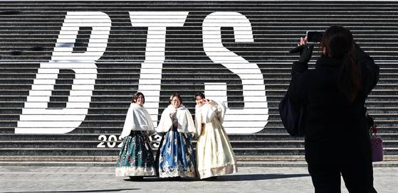 Tourists take a photo in front of a promotion for BTS's new album, "Arirang," at the Sejong Center for the Performing Arts in Jongno District, central Seoul, on Jan. 22. [YONHAP]